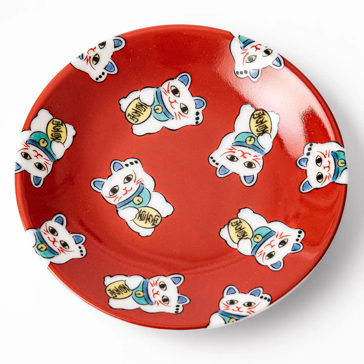 Round Japanese ceramic sauce dish with a red background decorated with playful maneki neko lucky cats, perfect for serving soy sauce or small condiments.