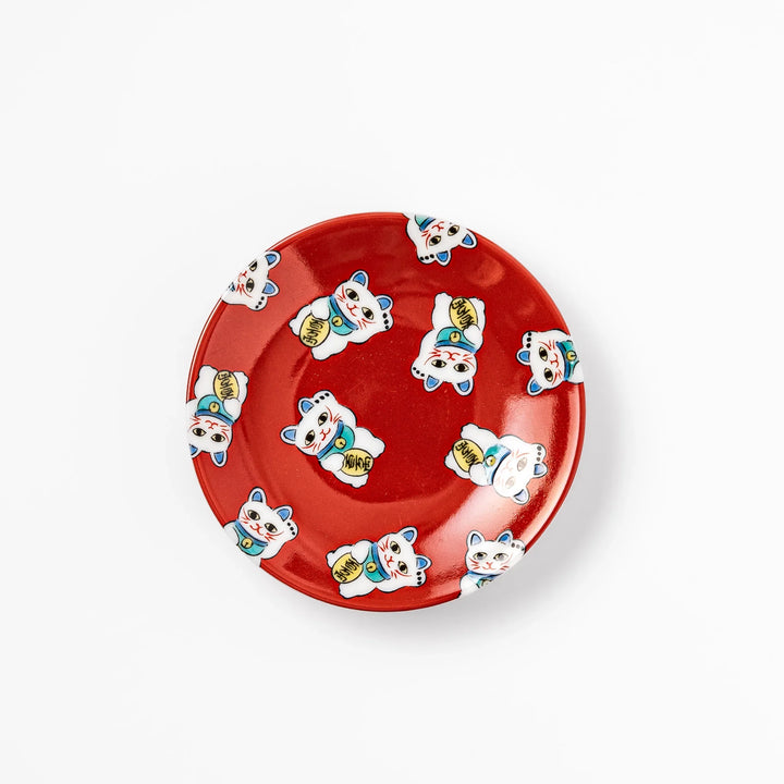 Round Japanese ceramic sauce dish with a red background decorated with playful maneki neko lucky cats, perfect for serving soy sauce or small condiments.