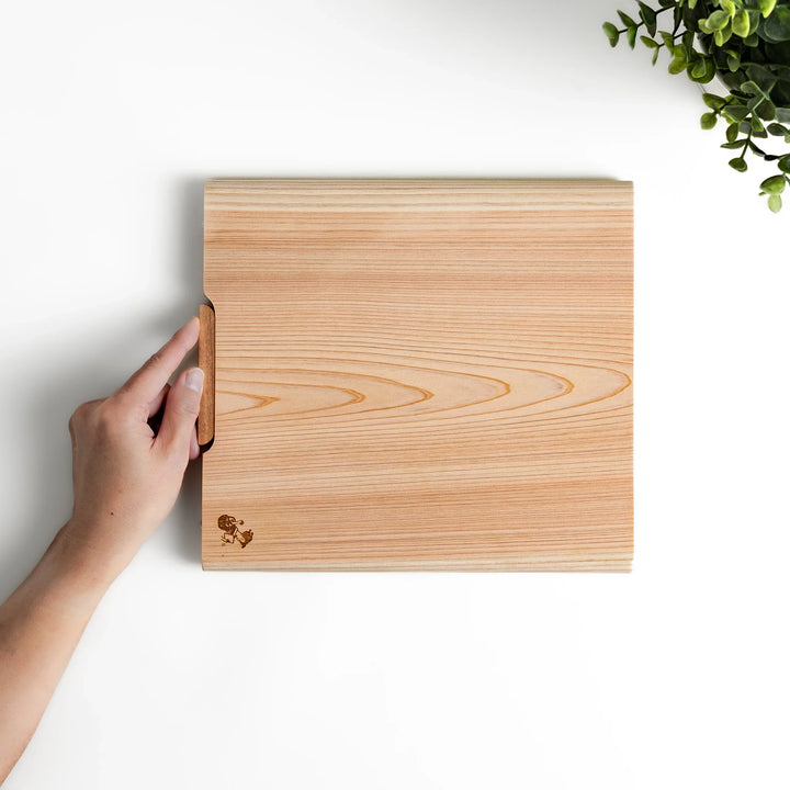 Medium Hinoki wood cutting board with natural grain, side handle, engraved motif, and smooth finish, crafted in Japan