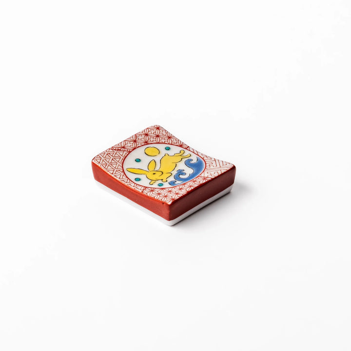 Rectangular Japanese ceramic chopstick rest with red geometric pattern and moon rabbit motif, blending playful design and tradition for a charming table accent.