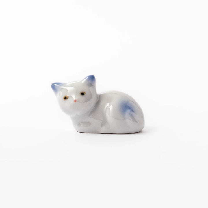 White ceramic chopstick rest shaped like a reclining cat with soft blue accents and a glossy finish.