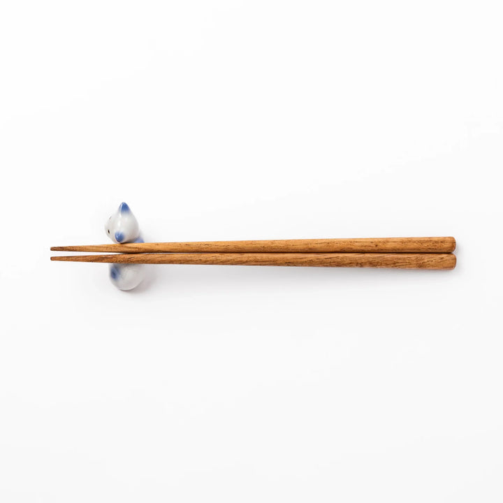 White ceramic chopstick rest shaped like a reclining cat with soft blue accents and a glossy finish.
