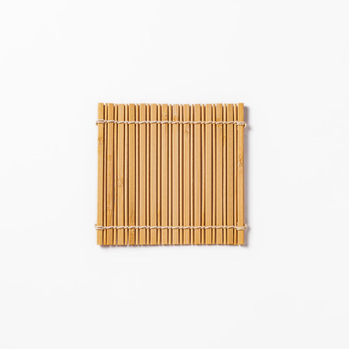 Natural finish bamboo coaster with uniform vertical slats and white cord ties, bringing a warm, organic accent to your Japanese-style table setting.