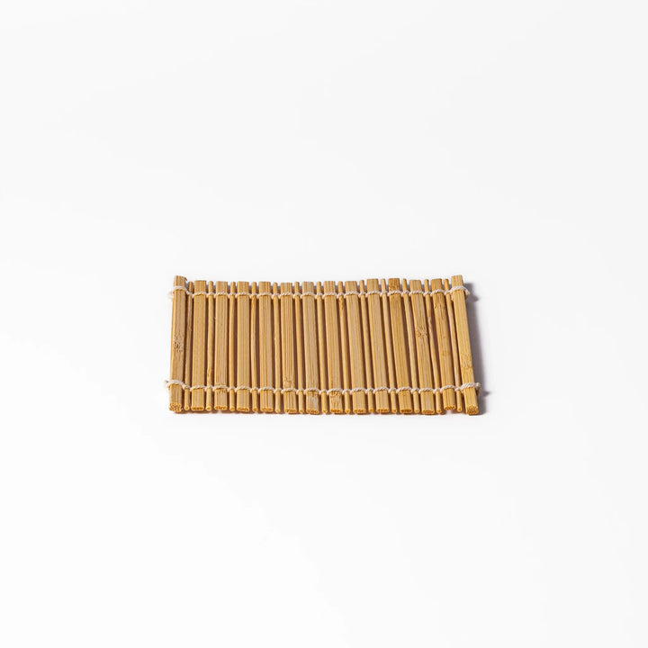 Natural finish bamboo coaster with uniform vertical slats and white cord ties, bringing a warm, organic accent to your Japanese-style table setting.