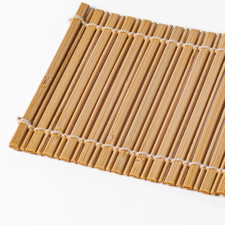Natural finish bamboo coaster with uniform vertical slats and white cord ties, bringing a warm, organic accent to your Japanese-style table setting.