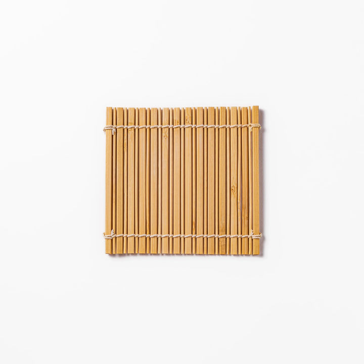 Natural finish bamboo coaster with uniform vertical slats and white cord ties, bringing a warm, organic accent to your Japanese-style table setting.