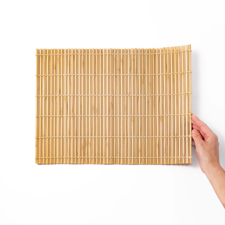 Natural finish bamboo table mat with slim vertical slats and white cord binding, offering a clean, earthy touch to traditional Japanese table settings.
