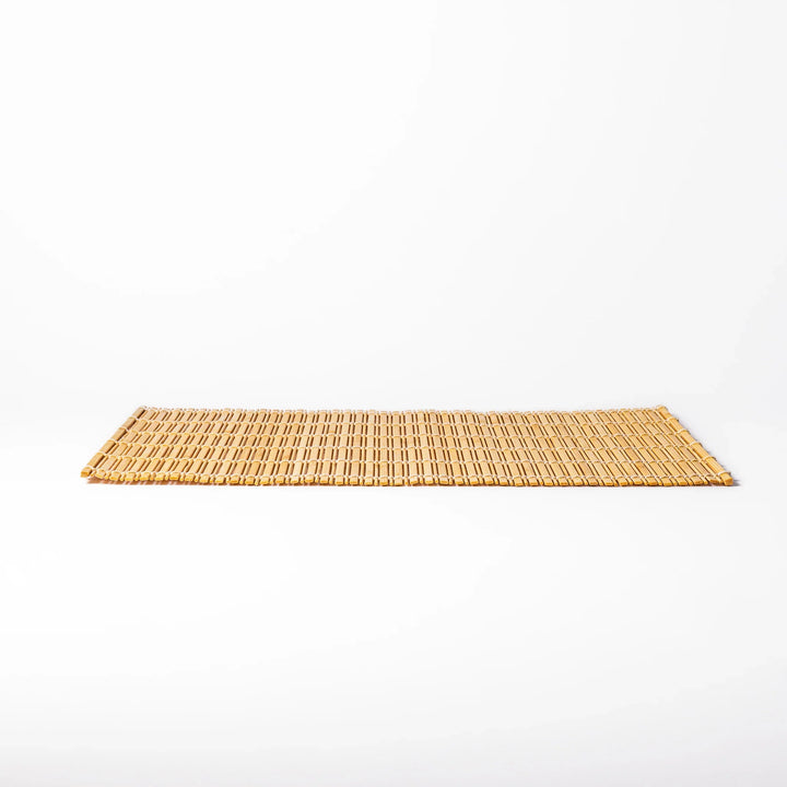 Natural finish bamboo table mat with slim vertical slats and white cord binding, offering a clean, earthy touch to traditional Japanese table settings.