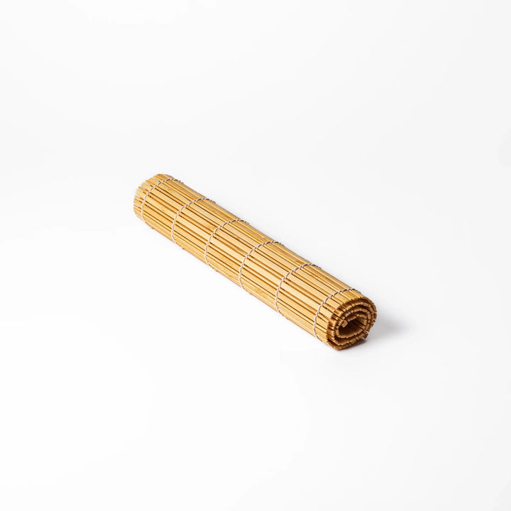 Natural finish bamboo table mat with slim vertical slats and white cord binding, offering a clean, earthy touch to traditional Japanese table settings.