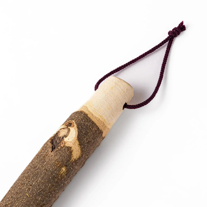 Natural sansho wood pestle featuring bark textures and a burgundy hanging cord, ideal for traditional Japanese grinding.