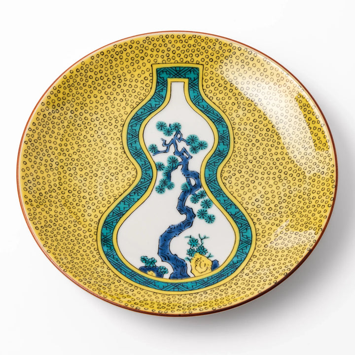 Japanese dessert plate featuring a yellow patterned background with a gourd-shaped center, showcasing a blue pine tree and green foliage.