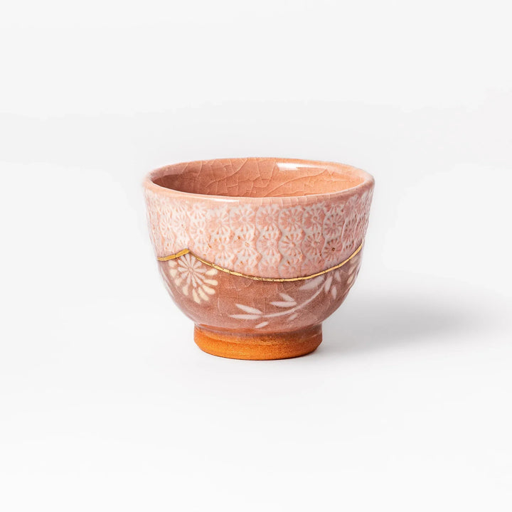 Ceramic tea cup with a crackled pink glaze, floral patterns, and a soft gold accent line blending traditional charm with handmade warmth.