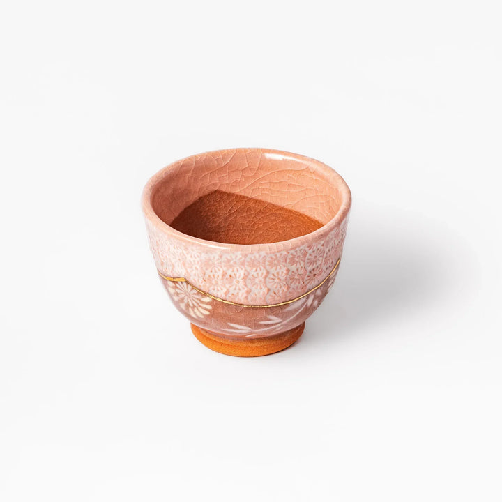 Ceramic tea cup with a crackled pink glaze, floral patterns, and a soft gold accent line blending traditional charm with handmade warmth.