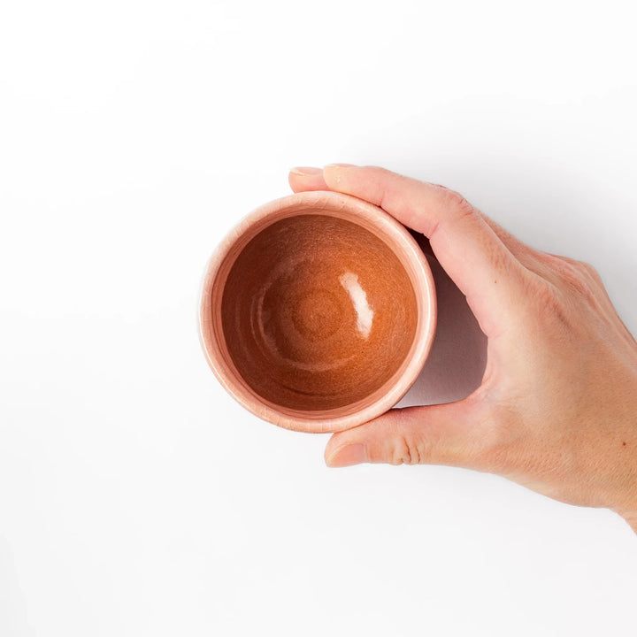 Ceramic tea cup with a crackled pink glaze, floral patterns, and a soft gold accent line blending traditional charm with handmade warmth.