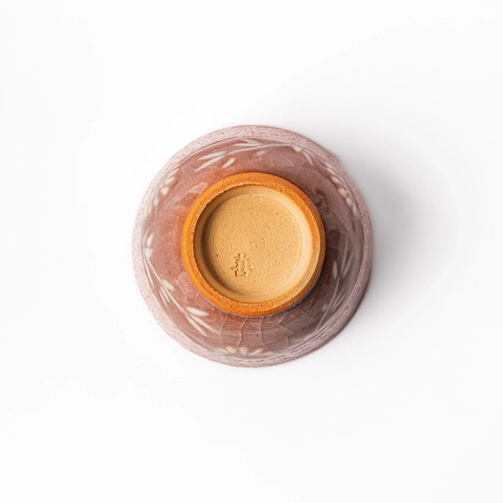 Ceramic tea cup with a crackled pink glaze, floral patterns, and a soft gold accent line blending traditional charm with handmade warmth.