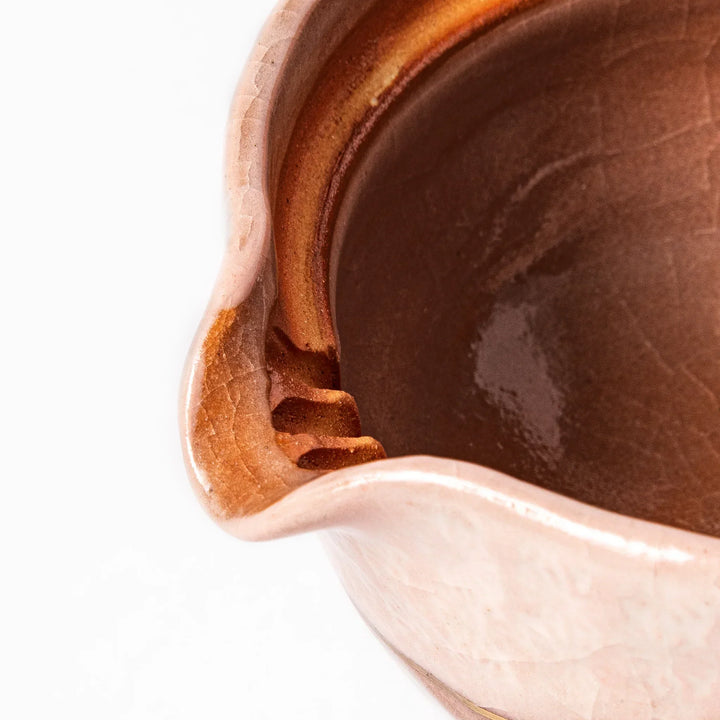 Ceramic teapot with a soft pink crackled glaze, floral patterns, and a curved spout accented by a hand-applied gold line for an artisanal touch.