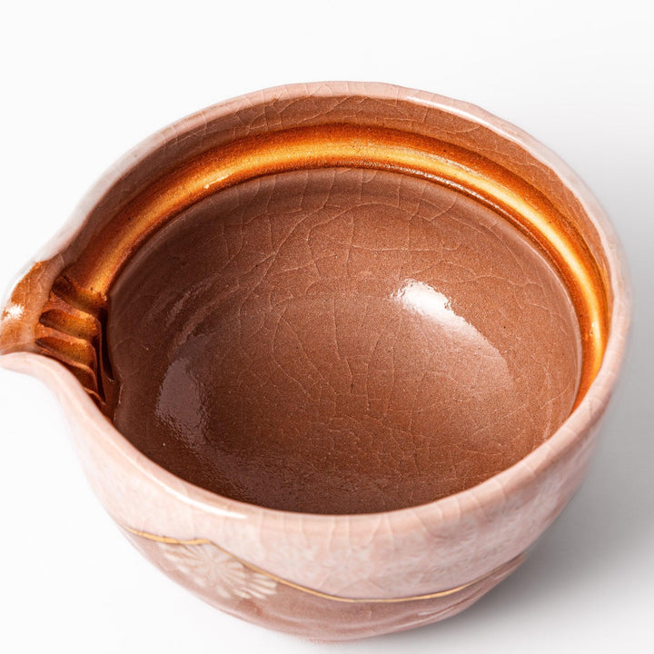 Ceramic teapot with a soft pink crackled glaze, floral patterns, and a curved spout accented by a hand-applied gold line for an artisanal touch.