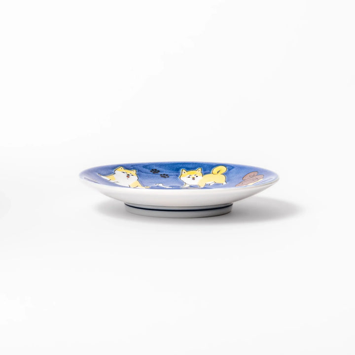Round Japanese ceramic sauce dish with a deep blue background decorated with playful Shiba Inu dogs, paw prints, and bones, perfect for condiments or snacks.