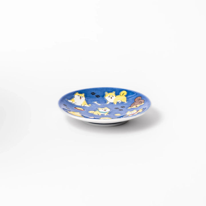 Round Japanese ceramic sauce dish with a deep blue background decorated with playful Shiba Inu dogs, paw prints, and bones, perfect for condiments or snacks.