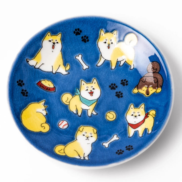 Round Japanese ceramic sauce dish with a deep blue background decorated with playful Shiba Inu dogs, paw prints, and bones, perfect for condiments or snacks.