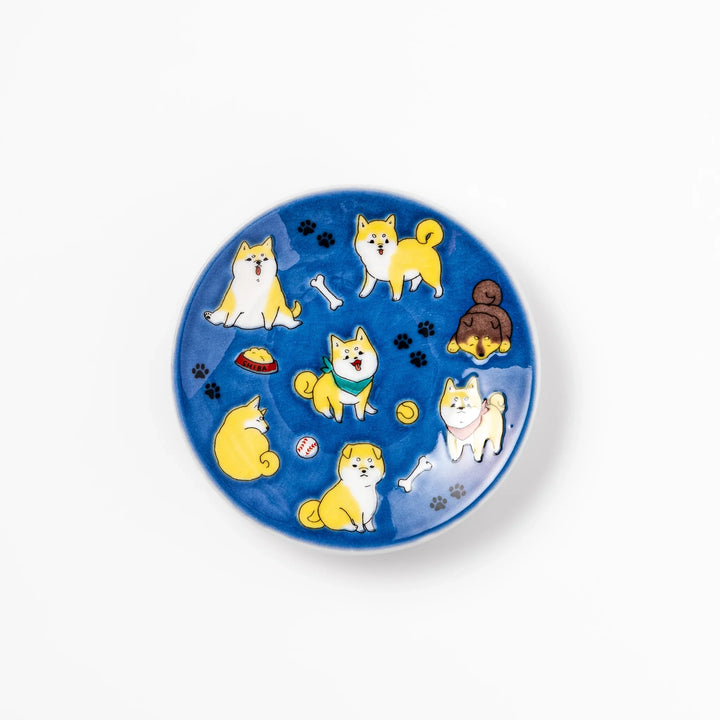 Round Japanese ceramic sauce dish with a deep blue background decorated with playful Shiba Inu dogs, paw prints, and bones, perfect for condiments or snacks.