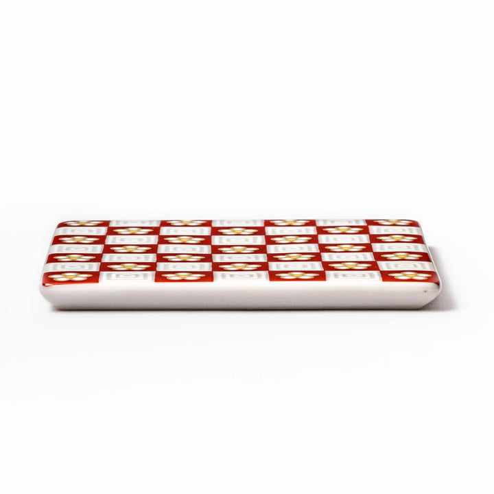 Square Japanese ceramic coaster with red and white checkered pattern decorated with plum blossom motifs, adding traditional charm to any dining table.