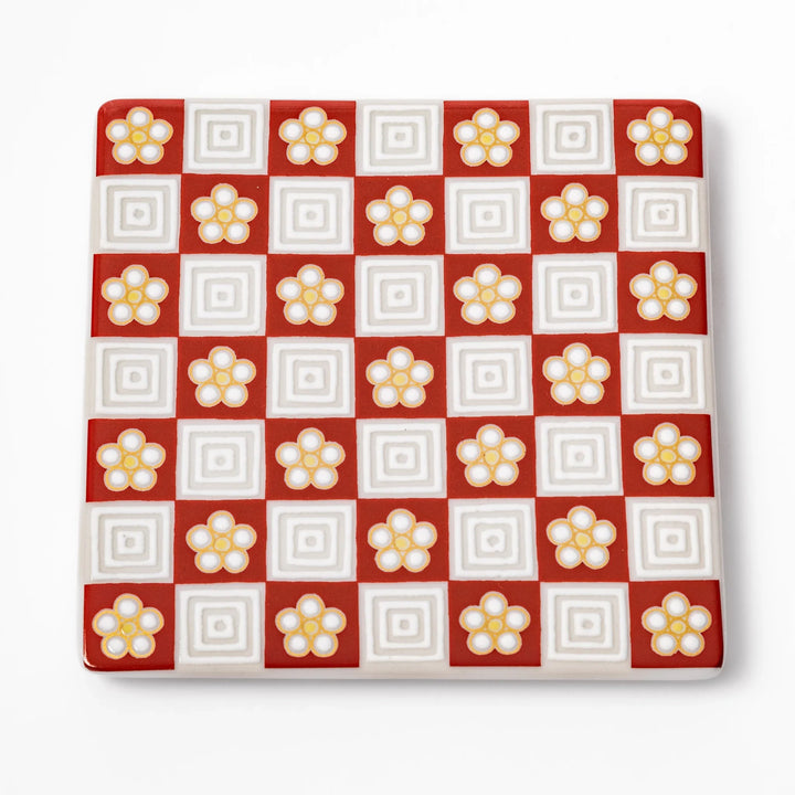 Square Japanese ceramic coaster with red and white checkered pattern decorated with plum blossom motifs, adding traditional charm to any dining table.