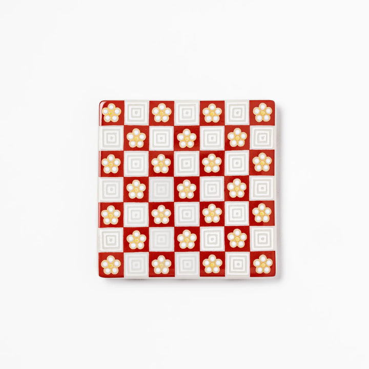 Square Japanese ceramic coaster with red and white checkered pattern decorated with plum blossom motifs, adding traditional charm to any dining table.