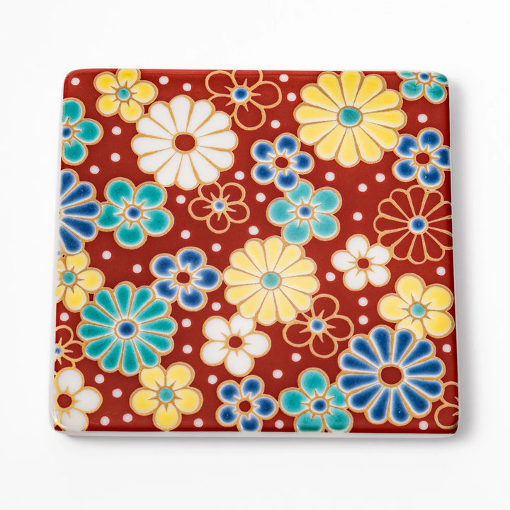 Square Japanese ceramic coaster with a red background decorated with colorful plum and chrysanthemum blossoms, adding elegance and tradition to table settings.