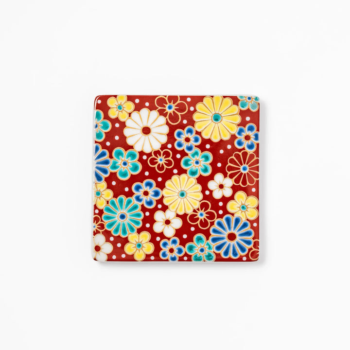 Square Japanese ceramic coaster with a red background decorated with colorful plum and chrysanthemum blossoms, adding elegance and tradition to table settings.