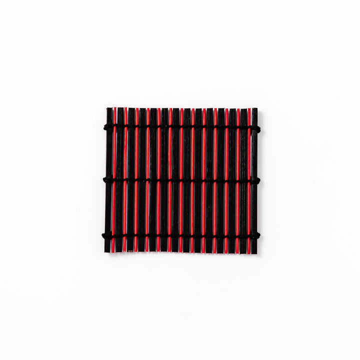 Red and black bamboo coaster with slim vertical slats and black cord ties, ideal for adding a striking accent to Japanese-style drink settings.