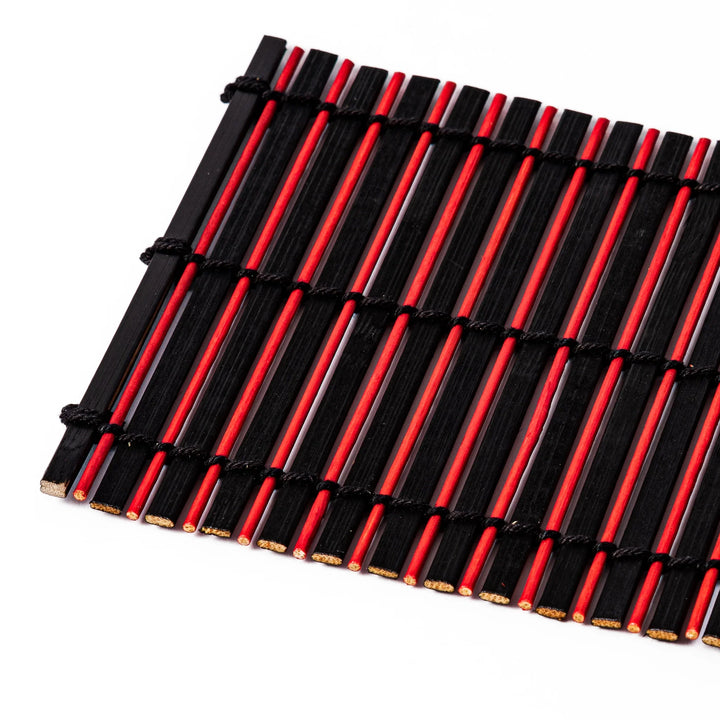 Red and black bamboo coaster with slim vertical slats and black cord ties, ideal for adding a striking accent to Japanese-style drink settings.