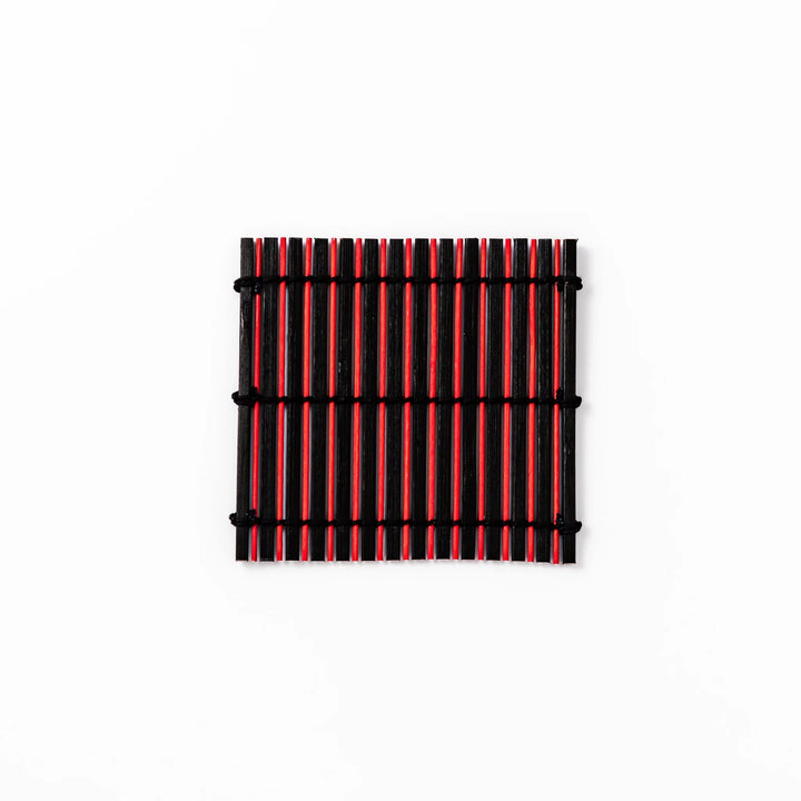 Red and black bamboo coaster with slim vertical slats and black cord ties, ideal for adding a striking accent to Japanese-style drink settings.