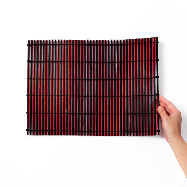 Red and black bamboo table mat with tightly spaced slats and black cord binding, adding bold color and texture to modern Japanese table settings.