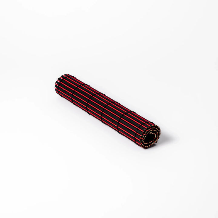 Red and black bamboo table mat with tightly spaced slats and black cord binding, adding bold color and texture to modern Japanese table settings.