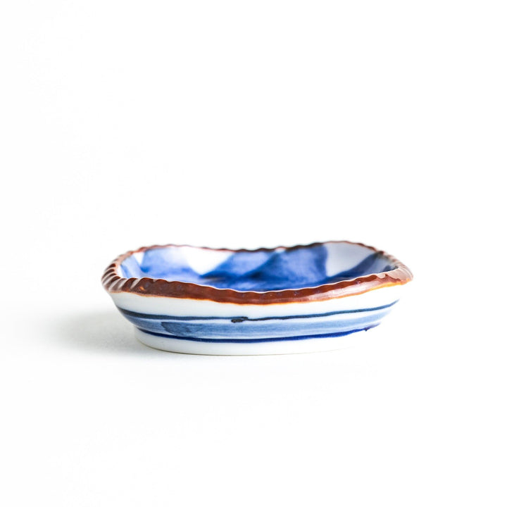 A round plate featuring a large, bold blue flower with a textured brown rim.