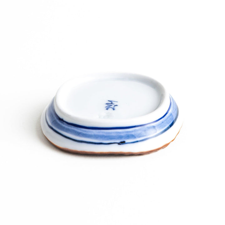 A round plate featuring a large, bold blue flower with a textured brown rim.