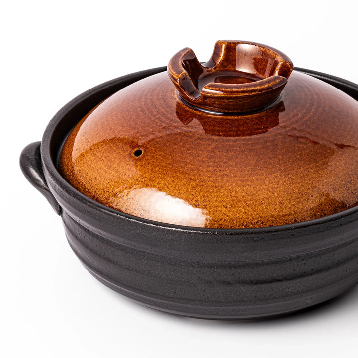 Japanese donabe clay pot with rustic brown glazed lid and black base, induction compatible and perfect for family hot pot meals.