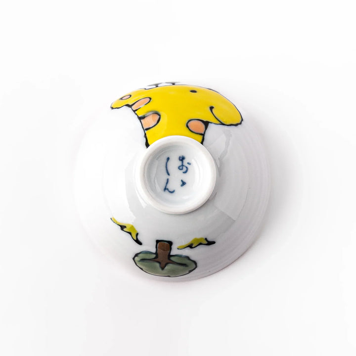 White ceramic kids rice bowl with smiling yellow giraffe illustration, vibrant yellow interior, round footed base