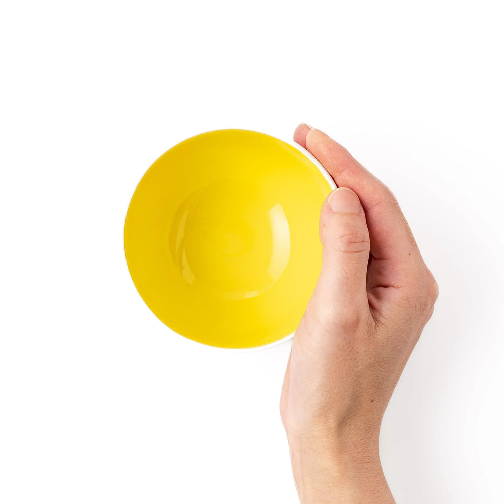 White ceramic kids rice bowl with smiling yellow giraffe illustration, vibrant yellow interior, round footed base