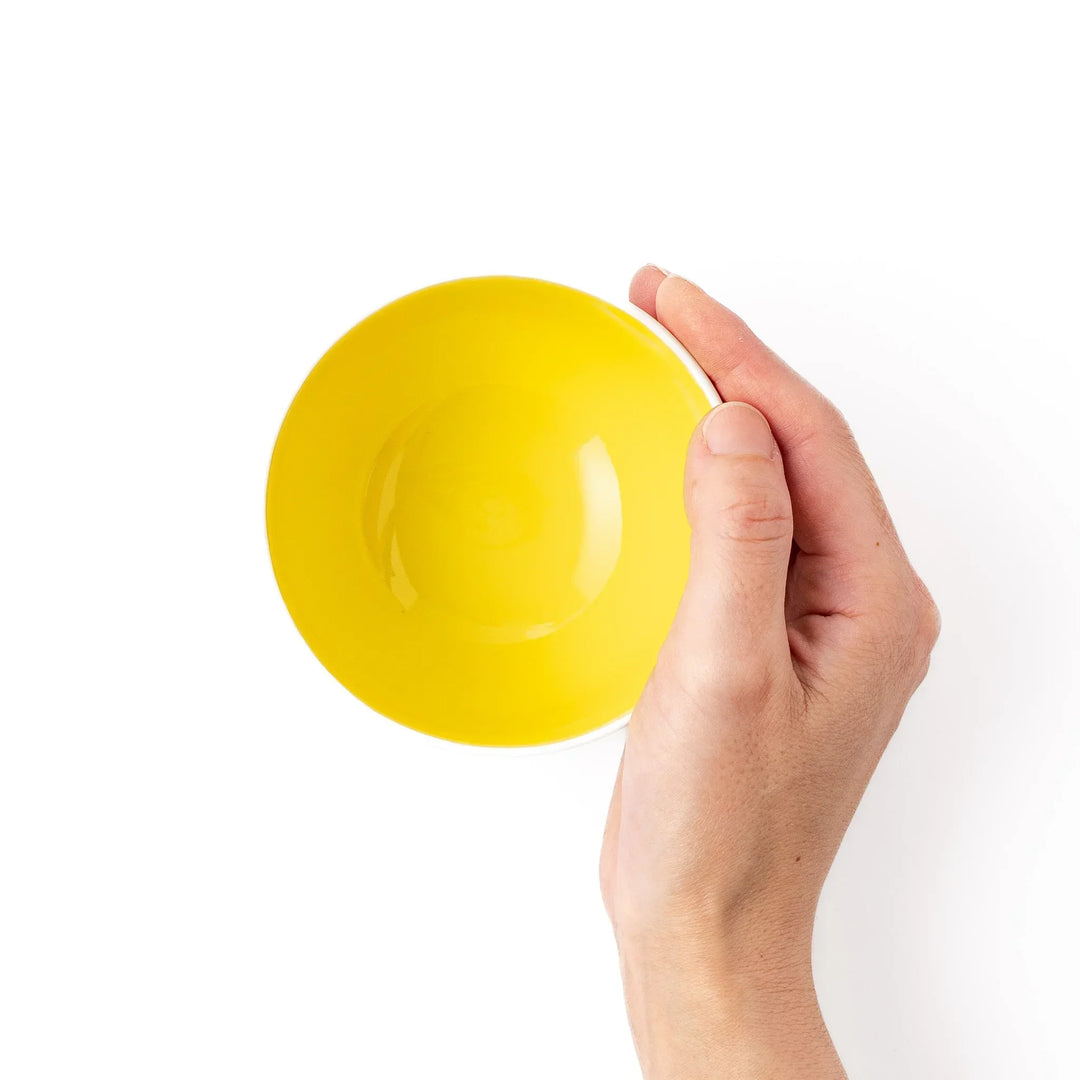 White ceramic kids rice bowl with smiling yellow giraffe illustration, vibrant yellow interior, round footed base