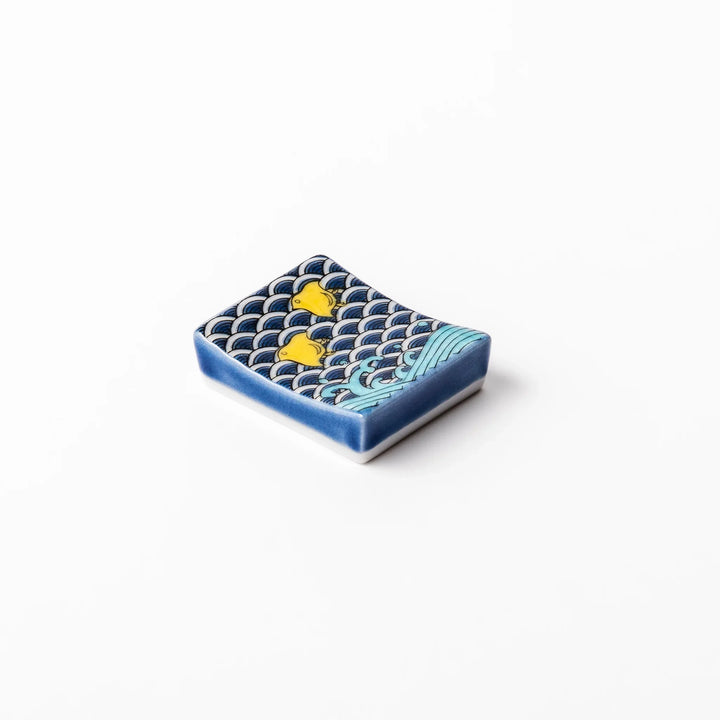 Rectangular Japanese ceramic chopstick rest decorated with a blue wave pattern and playful yellow shorebirds, adding charm and tradition to dining tables.