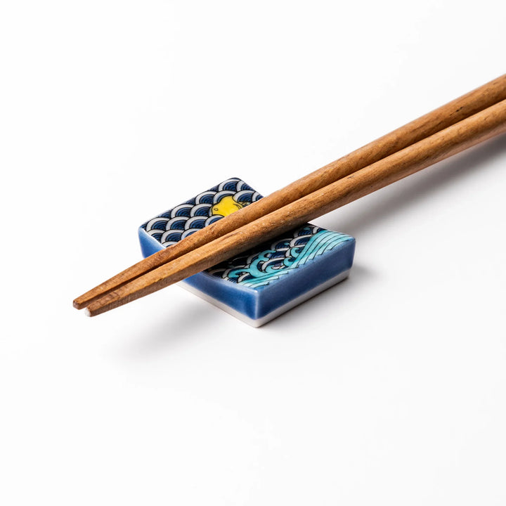 Rectangular Japanese ceramic chopstick rest decorated with a blue wave pattern and playful yellow shorebirds, adding charm and tradition to dining tables.