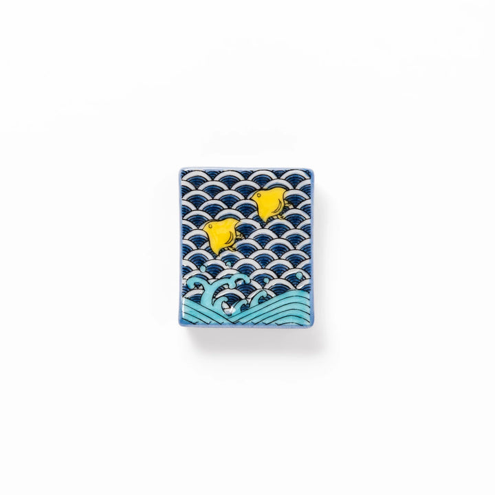 Rectangular Japanese ceramic chopstick rest decorated with a blue wave pattern and playful yellow shorebirds, adding charm and tradition to dining tables.
