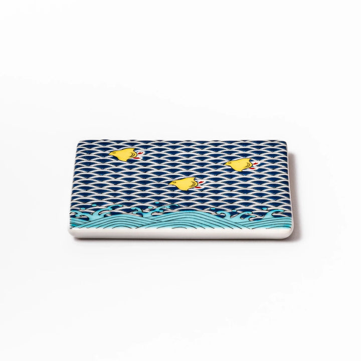 Square Japanese ceramic coaster with traditional blue wave pattern and yellow shorebirds, combining artistry and function for stylish dining table settings.