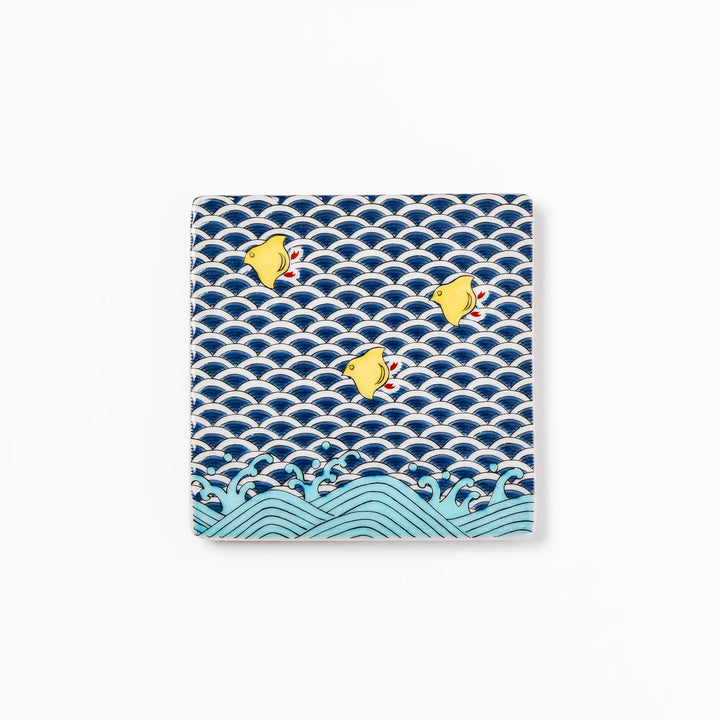 Square Japanese ceramic coaster with traditional blue wave pattern and yellow shorebirds, combining artistry and function for stylish dining table settings.