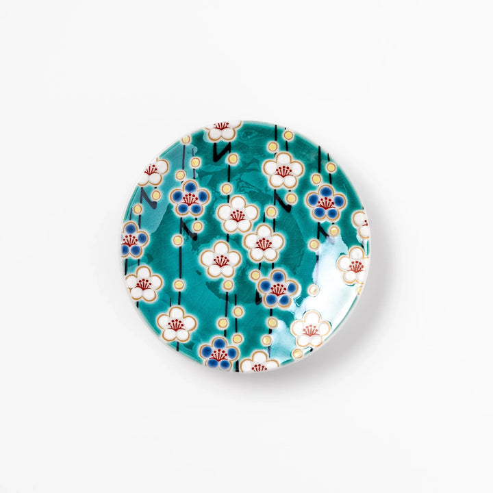 Round Japanese ceramic sauce dish with teal background, decorated with white and blue plum blossom motifs, perfect for serving condiments or small bites.