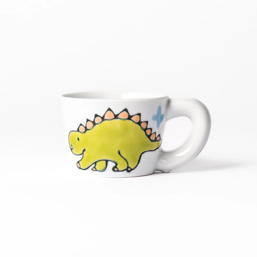 White ceramic kids mug featuring green stegosaurus dinosaur with round handle, shown on white background