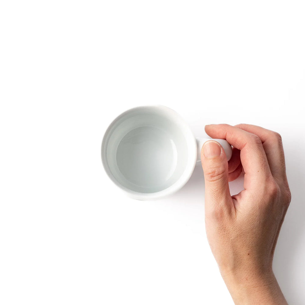White ceramic kids mug featuring green stegosaurus dinosaur with round handle, shown on white background