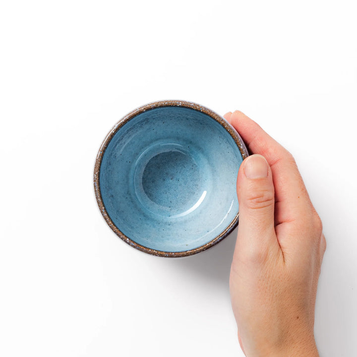 Terracotta blue ceramic tea cup with rustic brown rim, handcrafted in Japan for serving green tea, coffee, or everyday hot drinks.